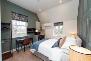 a bedroom with a bed and a desk and two windows at The Station at Shustoke - Birmingham Airport & NEC in Shustoke