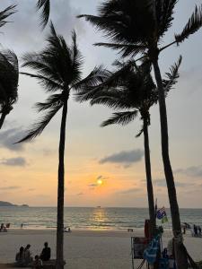 a group of people sitting on a beach with palm trees at Patong Beach Verve in Patong Beach