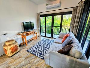 a living room with a couch and a flat screen tv at Anusorn Villas & Garden Oasis - Peaceful Chiang Mai Hideaway in Ban Ton Chok