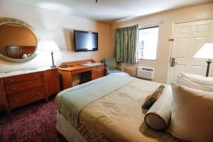 a hotel room with a bed and a desk and a mirror at Heritage Inn La Mesa in La Mesa