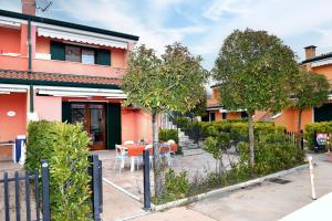 a red building with a table and trees in front of it at Villaggio dei Fiori in Caorle