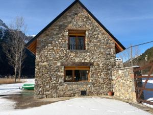 a stone building with a window in the snow at Borda del Llano in Bielsa