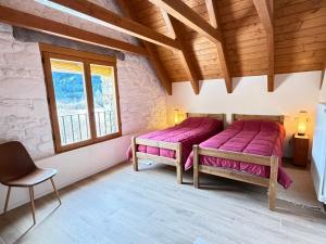two beds in a room with wooden ceilings and windows at Borda del Llano in Bielsa