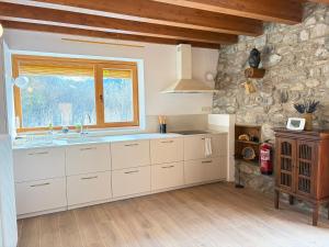a kitchen with white cabinets and a stone wall at Borda del Llano in Bielsa