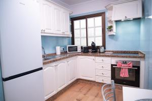 a kitchen with white cabinets and blue walls at El Hierro Bed in Valverde +11 photos