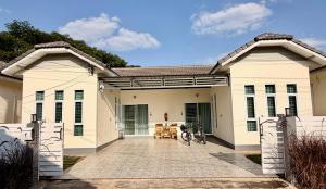 a large white house with a driveway at Khwanlom House in Lampang