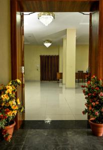 an open door to a hallway with flowers in a building at The Shrine Hotel in Godarpura