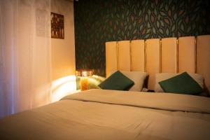 a bedroom with a large white bed with green pillows at Le 8 Suite Spa Privative Sauna et Jacuzzi parking gratuit in Mâcon