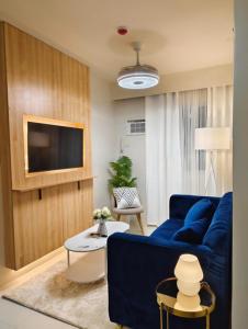 a living room with a blue couch and a tv at JB Casa del Alivio in Butuan