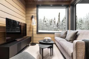 a living room with a couch and a tv at Bimmel Arctic Suite by PolarVillas in Kittilä