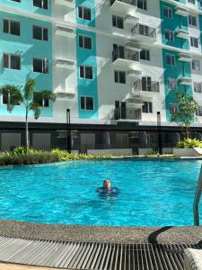 a man swimming in a swimming pool in front of a building at Our Space in CasaMira Towers Mandaue Cebu in Mandaue City