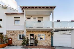 a white house with a balcony and a garage at O Lar de Laura Casa familiar para escapada tranquila con piscina y sala de juegos cerca de Vigo in Vigo