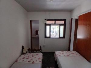 a small room with two beds and a window at Cantinho da Dê in Anchieta