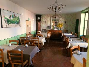 a dining room with tables and chairs and a clock at Beaune Hôtel in Beaune