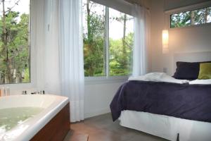 1 dormitorio con cama, bañera y ventana en Kaia Apart y Spa en Mar de las Pampas