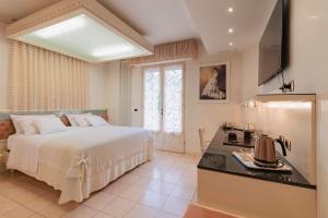 a bedroom with a large white bed and a kitchen at Hotel Matilde in Marina di Massa