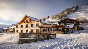 a large wooden building with snow on the ground at Hôtel - Restaurant Le Couchetat in La Bresse