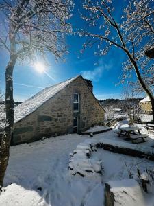 a barn covered in snow with the sun in the background at La Pastourelle en Lozère in Le Bacon