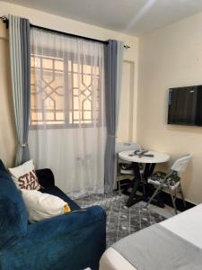 a living room with a blue couch and a table at Khalisee homes studio apartment 5 in Voi