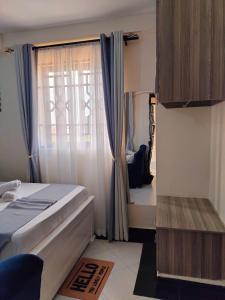 a bedroom with a bed and a window with curtains at Khalisee homes studio apartment 5 in Voi