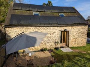 a stone house with an umbrella in front of it at Gîte du Portz in Ploërdut +2 photos
