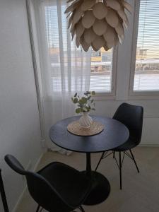 a table with chairs and a vase with flowers on it at Centrum Apartment Kokkola in Kokkola