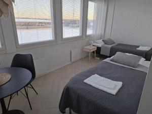 a room with two beds and a table and two windows at Centrum Apartment Kokkola in Kokkola