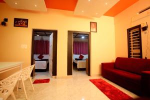 a living room with a red couch and a bedroom at Skylark Home in Mananthavady