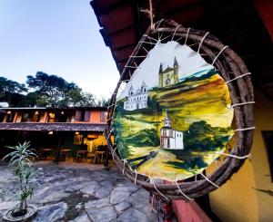 a painting of a building on the side of a building at Bituca Hostel e Café in Milho Verde