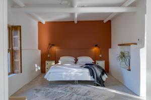 a bedroom with a white bed with an orange wall at Aarde in Barrydale
