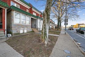 a tree in front of a house with a sidewalk at Cozy Baltimore Studio apts in Baltimore