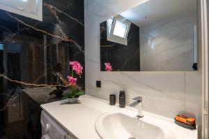 a bathroom with a sink and a mirror and pink flowers at Mystrali 2BD Modern Apt with Private Garden in Galatás