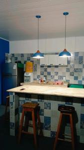 a kitchen with a counter with two bar stools at Chalé marlin azul in Icapuí +12 photos