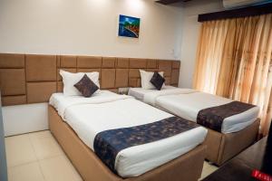 a hotel room with two beds and a window at Hotel The Al Aqsa in Chittagong