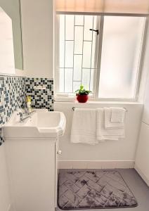a white bathroom with a sink and a window at Crescent House in Franschhoek