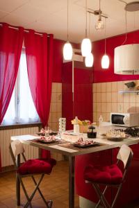 B&B Miele في San Fermo della Battaglia: مطبخ مع ستائر حمراء وطاولة مع كراسي