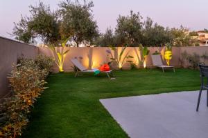 a yard with chairs and a fence with lights at Mystrali 2BD Modern Apt with Private Garden in Galatás +17 photos