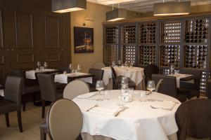 a restaurant with white tables and chairs and wine bottles at Hôtel de France Vire in Vire