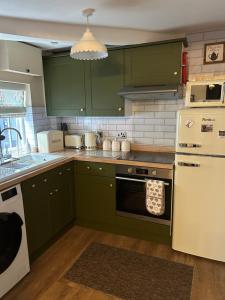 a kitchen with green cabinets and a white refrigerator at Beautiful Bell Cottage Heart of Bridgnorth Walk Everywhere in Bridgnorth