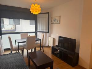 a living room with a table and a television at Relájate en Ramales de la Victoria, apartamento con piscina y parking in Ramales de la Victoria
