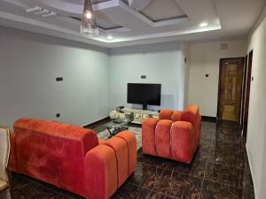 a living room with two couches and a flat screen tv at G and E Guesthouse in Kumba