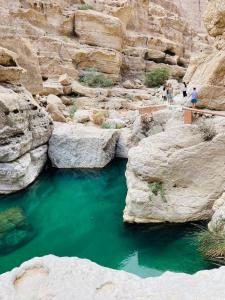 people walking on a bridge over a river in a canyon at House of Nomads - Hostel in Muscat