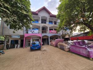 a blue car parked in front of a building at G and E Guesthouse in Kumba