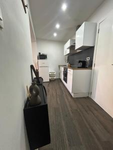 a small kitchen with white cabinets and wooden floors at Appartement cosy à 5 min du centre-ville in Liège