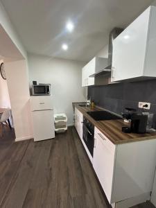 a kitchen with white cabinets and wooden floors at Appartement cosy à 5 min du centre-ville in Liège