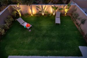 a backyard at night with two benches and lights at Mystrali 2BD Modern Apt with Private Garden in Galatás