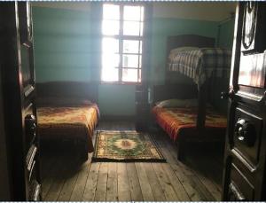 Habitación pequeña con 2 camas y ventana en Hostal La Chorrera, en Quito