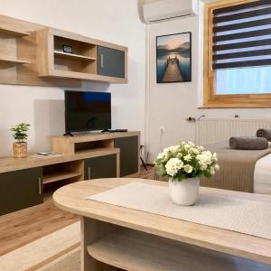 a living room with a table with a vase of flowers at GANCZ APARTMAN in Sárvár