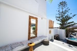 a mirror on the side of a white wall with a bench at Double M Adults Only in Ano Mera