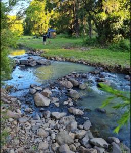 a creek with rocks and a person walking in a field at Giulia Guests Rooms in Beechmont